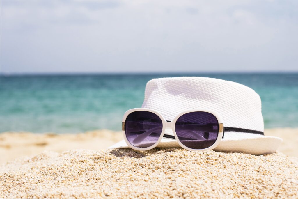 selective focus shot sunglasses white hat sandy beach 1024x684 1