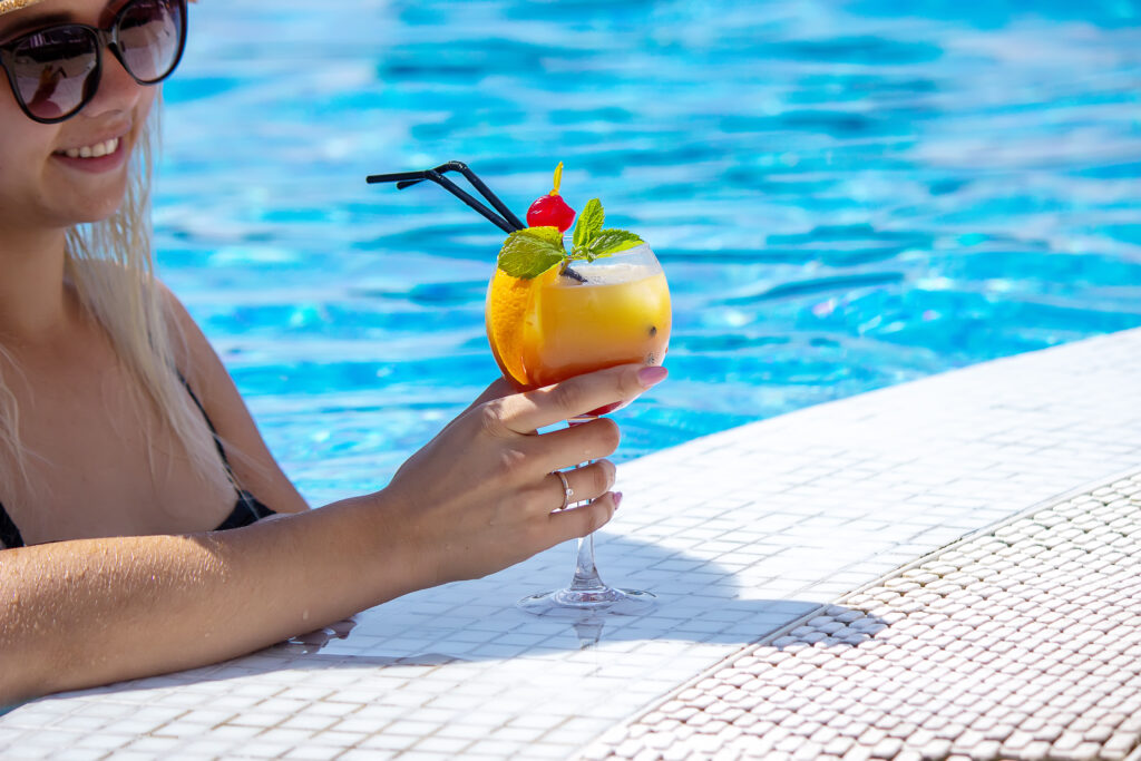 young woman is resting pool drinks cocktail with freshly squeezed orange 1024x683 1